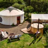 A yurt from above with a hot tub and outside seating.