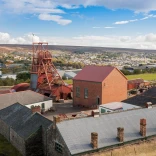 View of the Big Pit winding tower and outbuildings with the town in the background